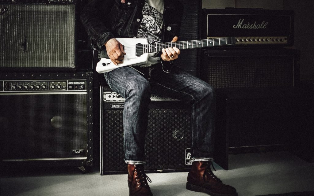 Image of Man Sitting on Guitar Amplifier Playing Electric Guitar