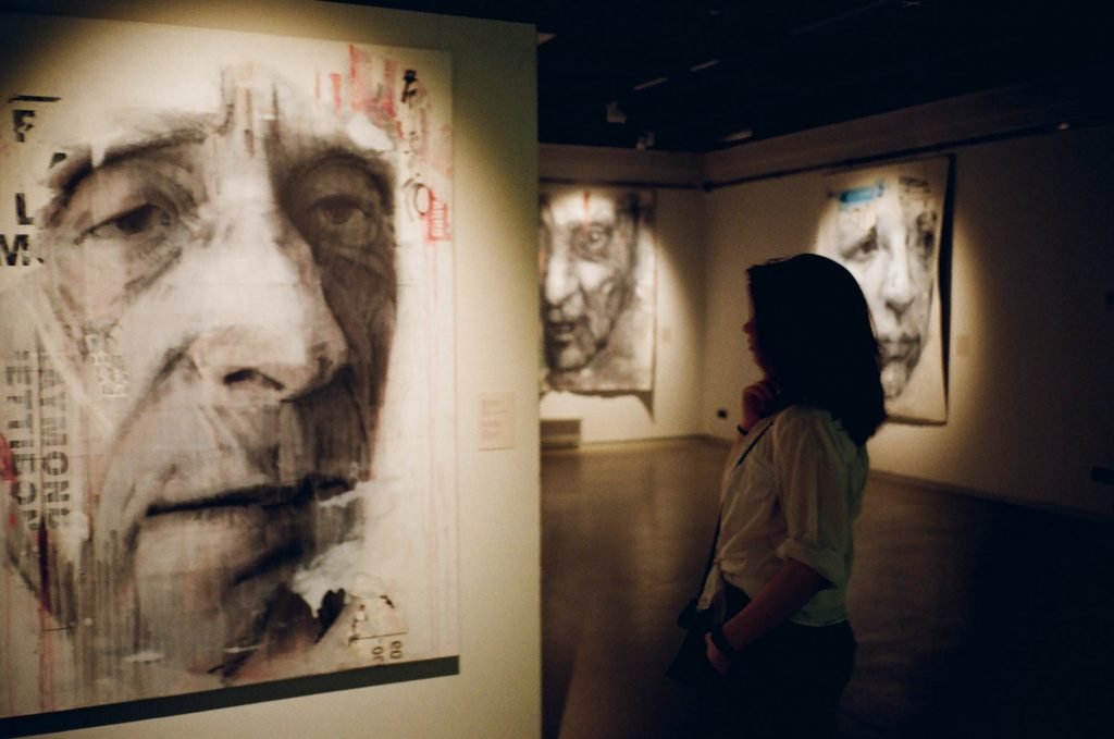 Image of Woman Standing in Front of Man's Painting