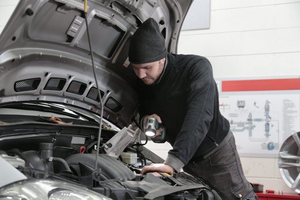 Image of Man in Black Jacket and Black Knit Cap Inspecting Car Engine