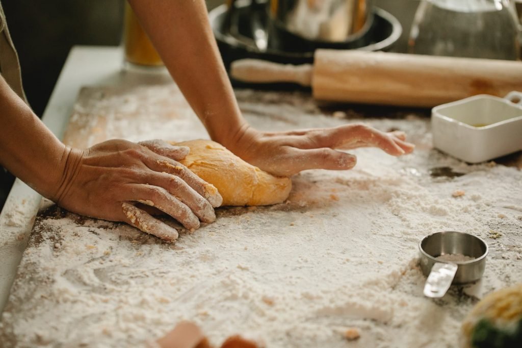 Image of Woman making pastry on table with flour