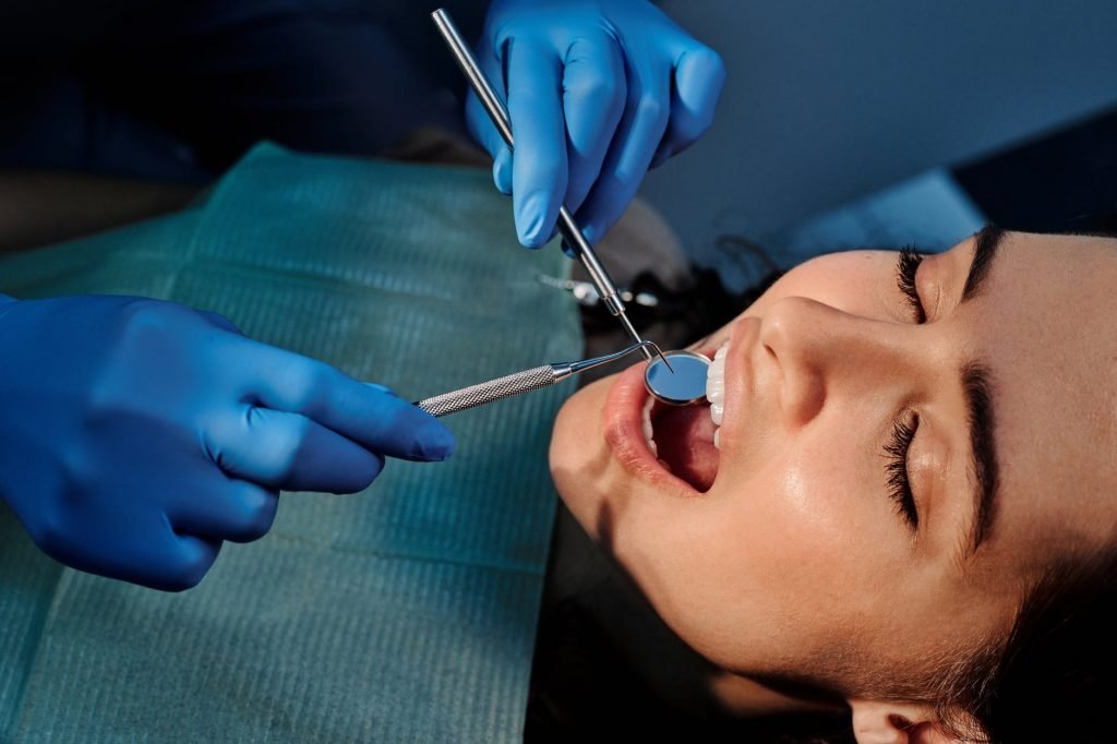 Image of A Person Wearing Blue Latex Gloves Holding a Mirror in a Woman's Mouth