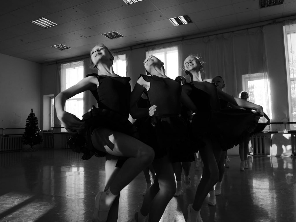 Image of Graceful ballerinas embracing while dancing in hall