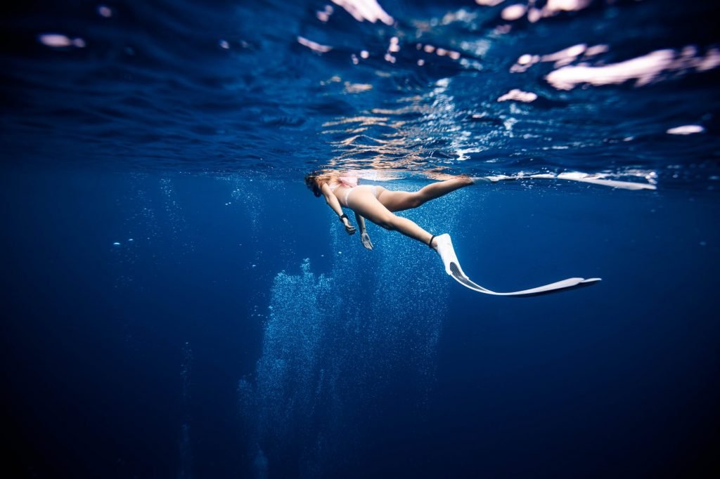 Image of Slim female diver in flippers swimming in blue sea