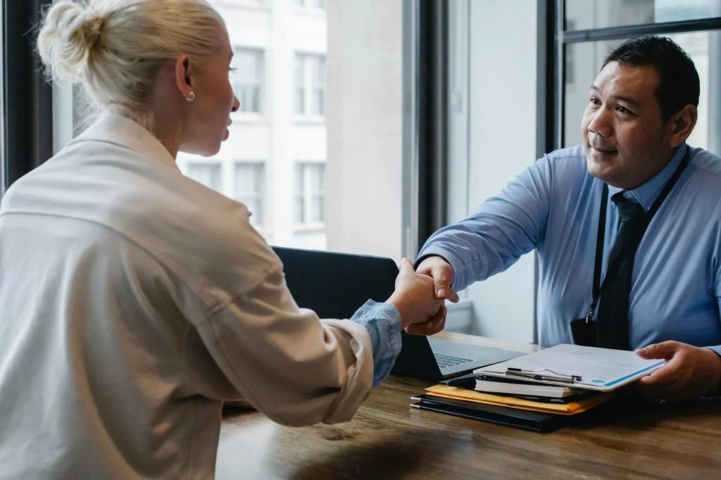 Image of Ethnic businessman shaking hand of applicant in office