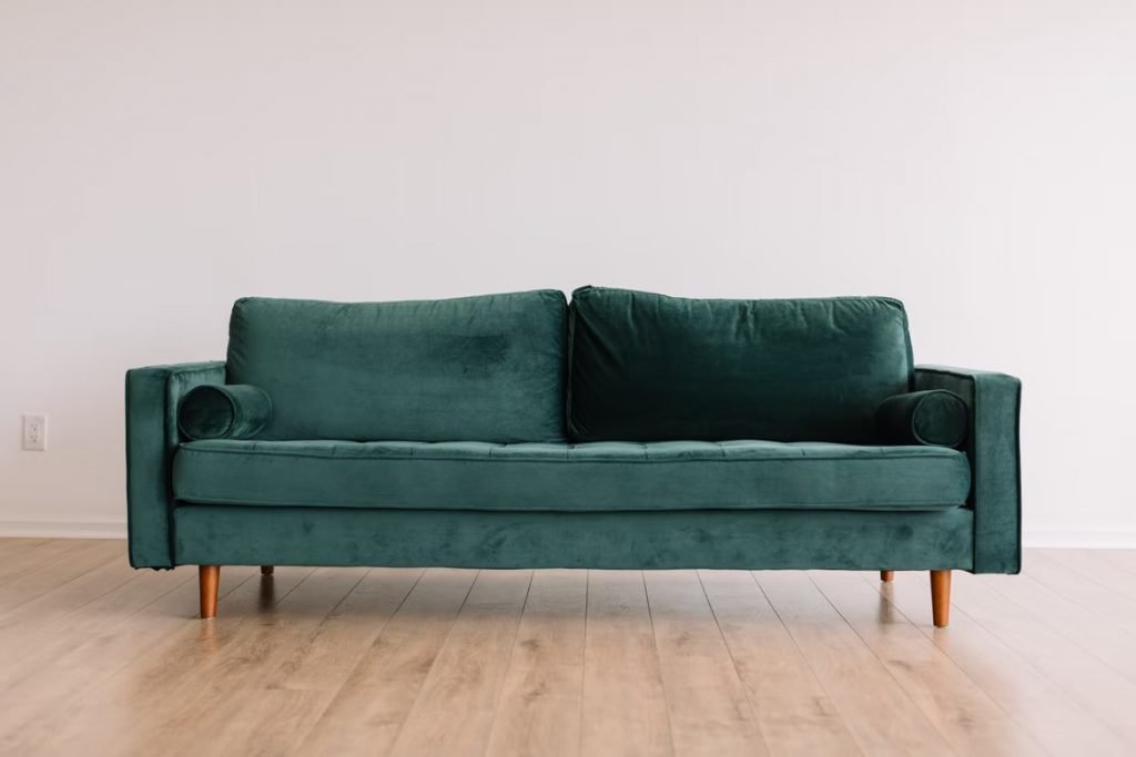 Image of Cool hipster green couch sofa with brown wooden legs on wooden floor