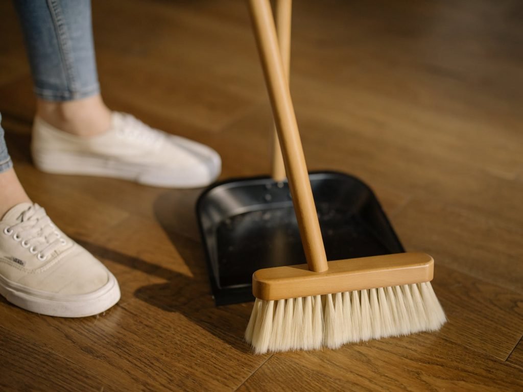 Image of Person Wearing White Pants and White Socks Standing Beside Brown Broom