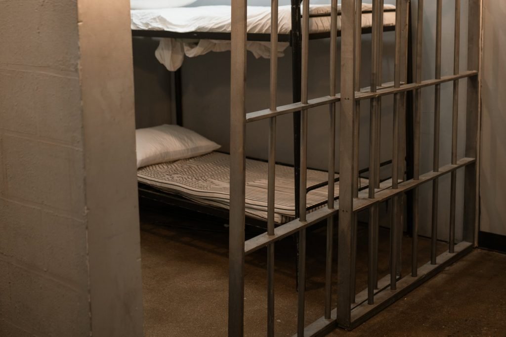 Image of A Bunk Bed With Striped Linen Behind Bars