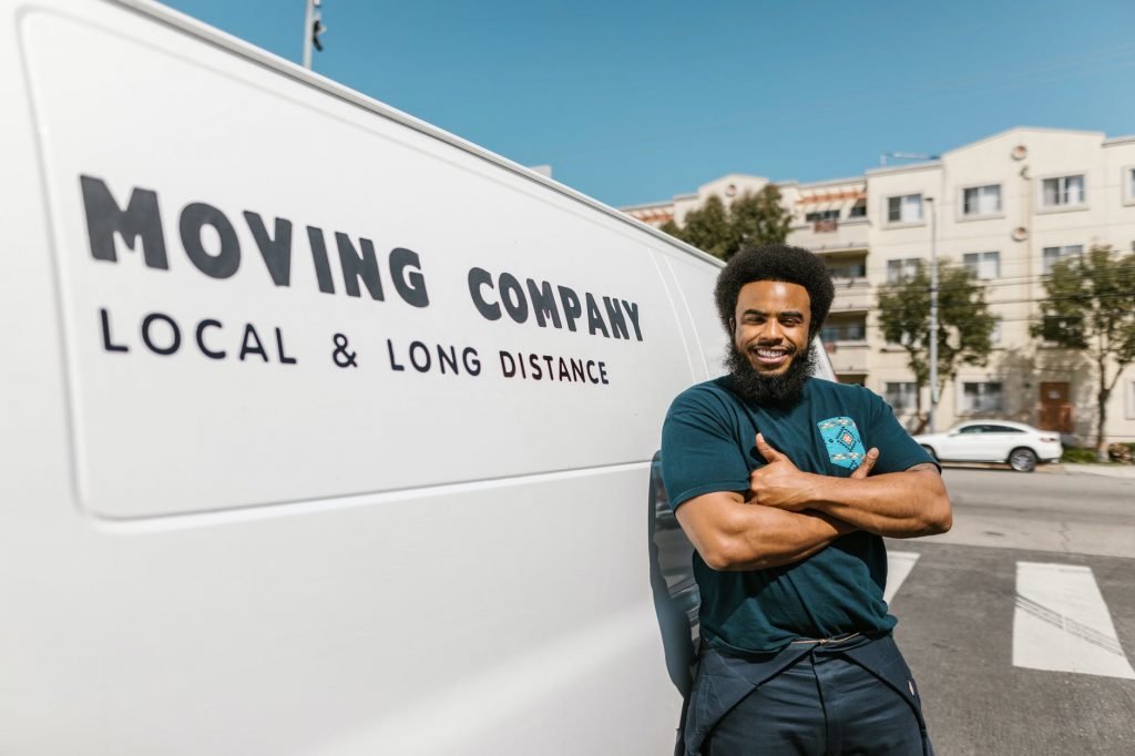 Image of Man in Blue T-shirt and Black Pants Standing Beside White Van