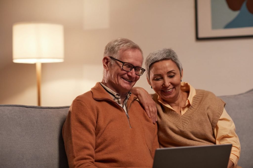 Image of Man and Woman Sitting on Sofa While Looking at a Laptop