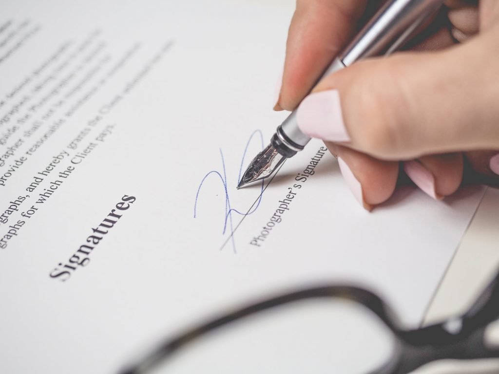 Image of Person Holding Silver Pen Signing Photographers Signature